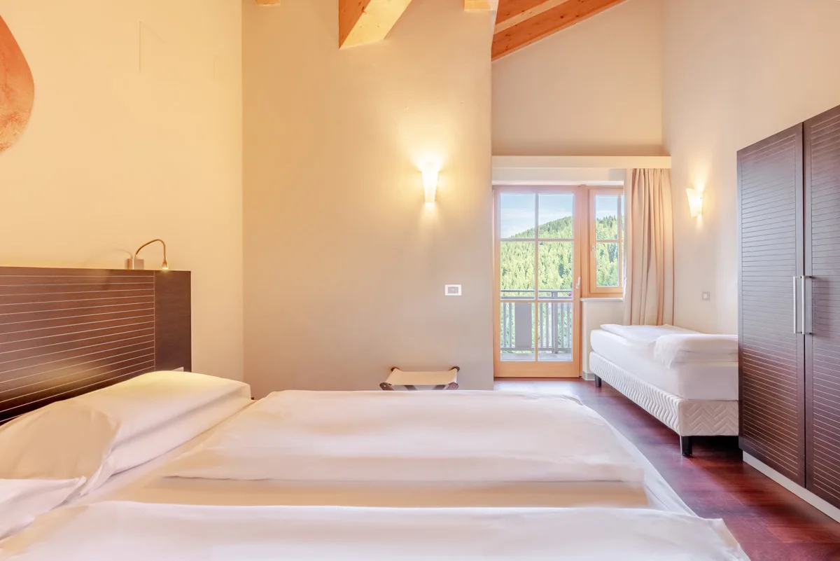 Camera con tetto in travi di legno, letto matrimoniale e balcone