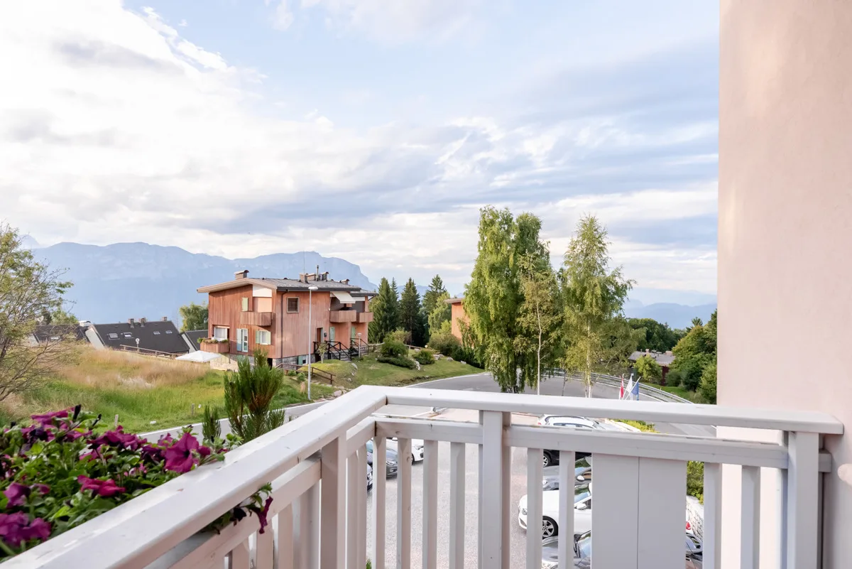 Balcone della camera con fiori e vista sulle montagne e il paese