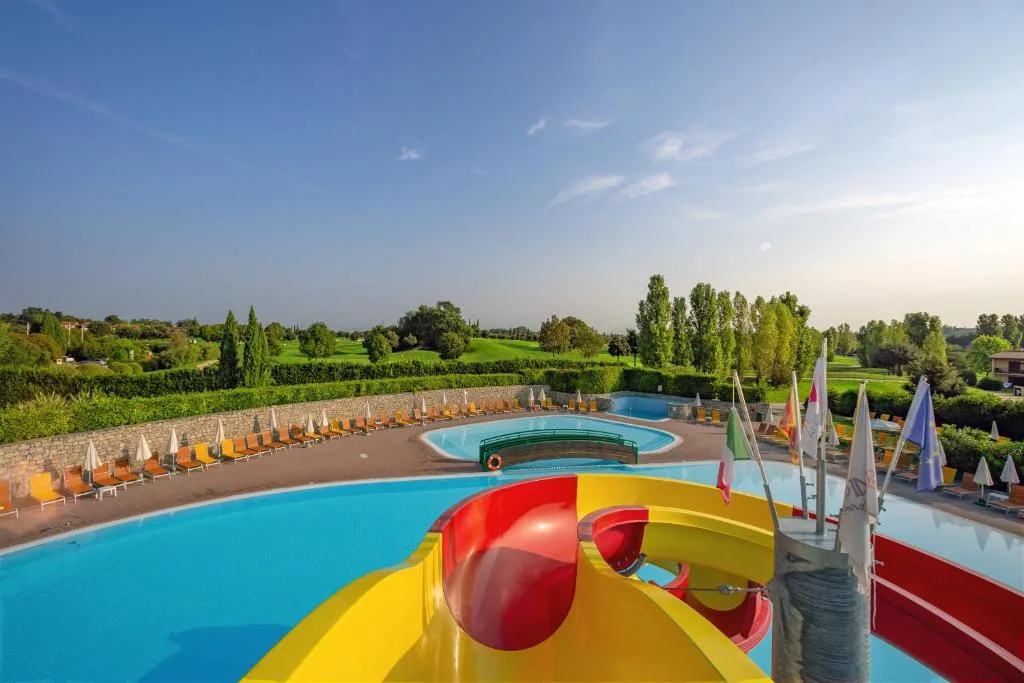 Vista dall'alto della piscina con scivolo colorato e campo da golf sullo sfondo