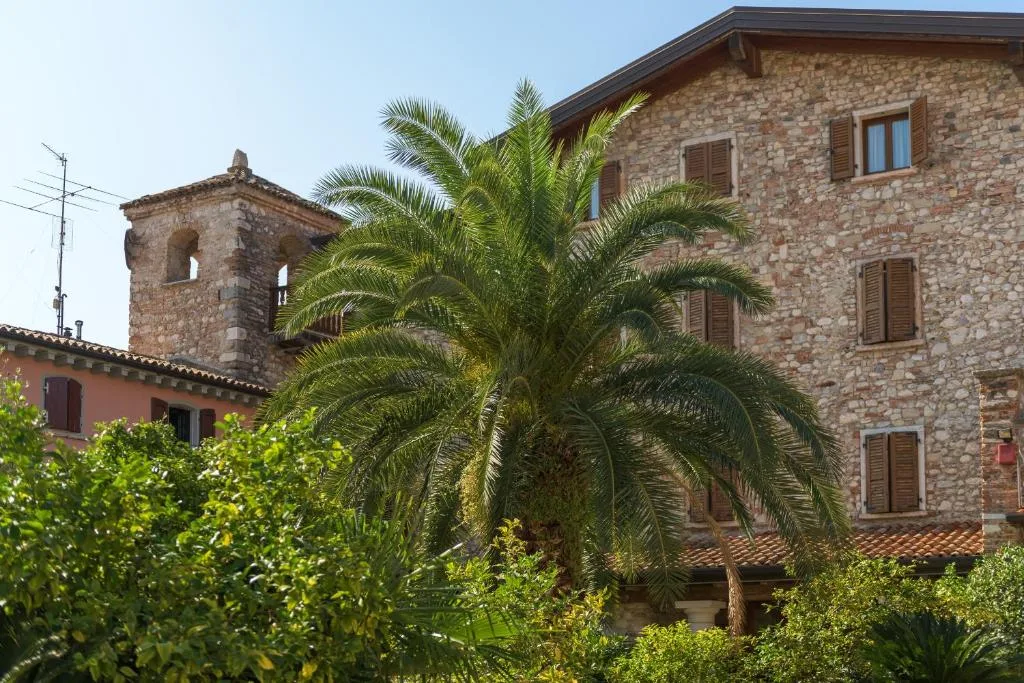 Edificio storico in pietra con palma e torre campanaria sotto il cielo azzurro