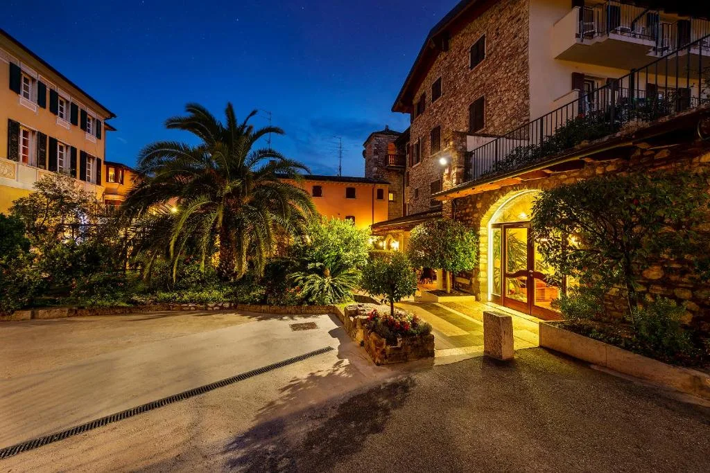 Ingresso dell'hotel illuminato al crepuscolo con giardino e palme
