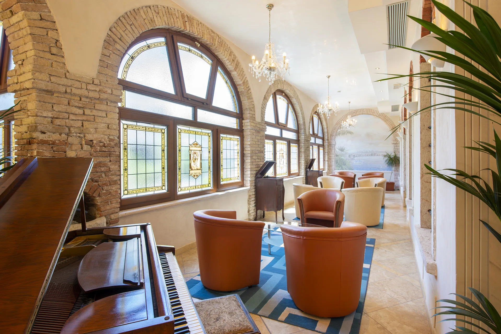 Elegante lounge con pianoforte, poltrone in pelle e vetrate ad arco decorate