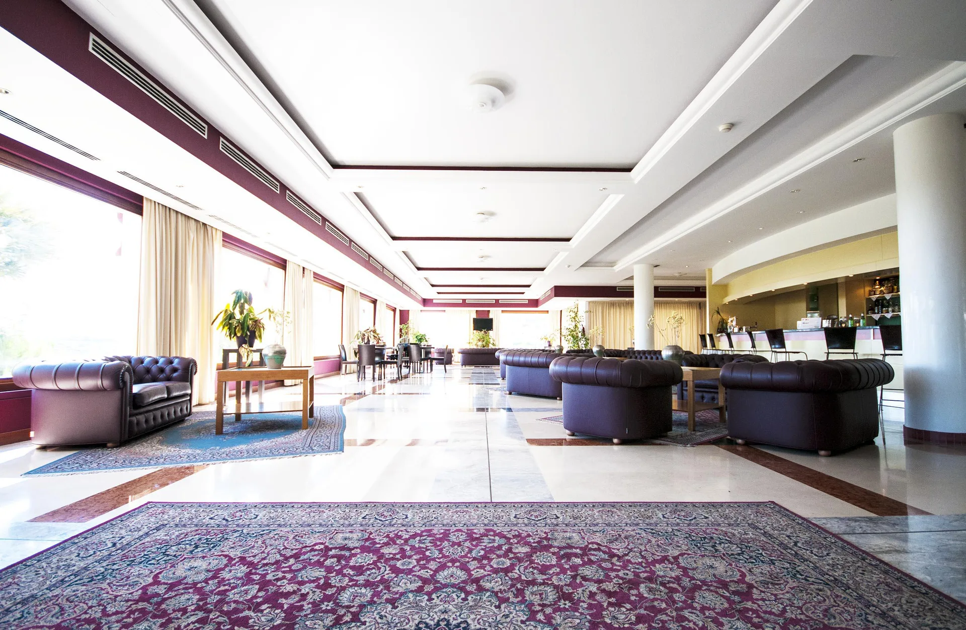 Ampia lounge con divani in pelle scuri, tappeti persiani e bancone bar