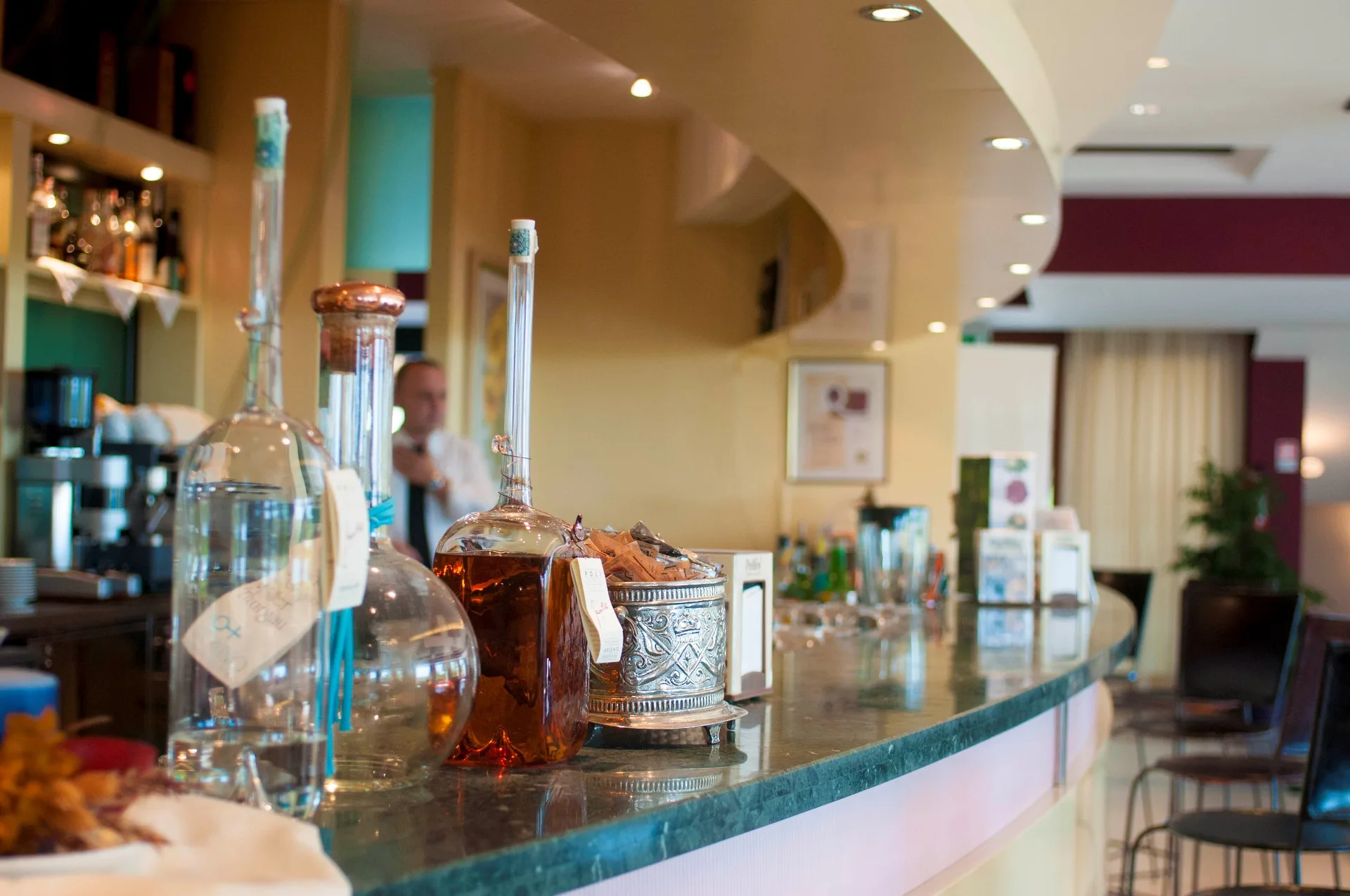 Bancone del bar con bottiglie di distillati e barman al lavoro