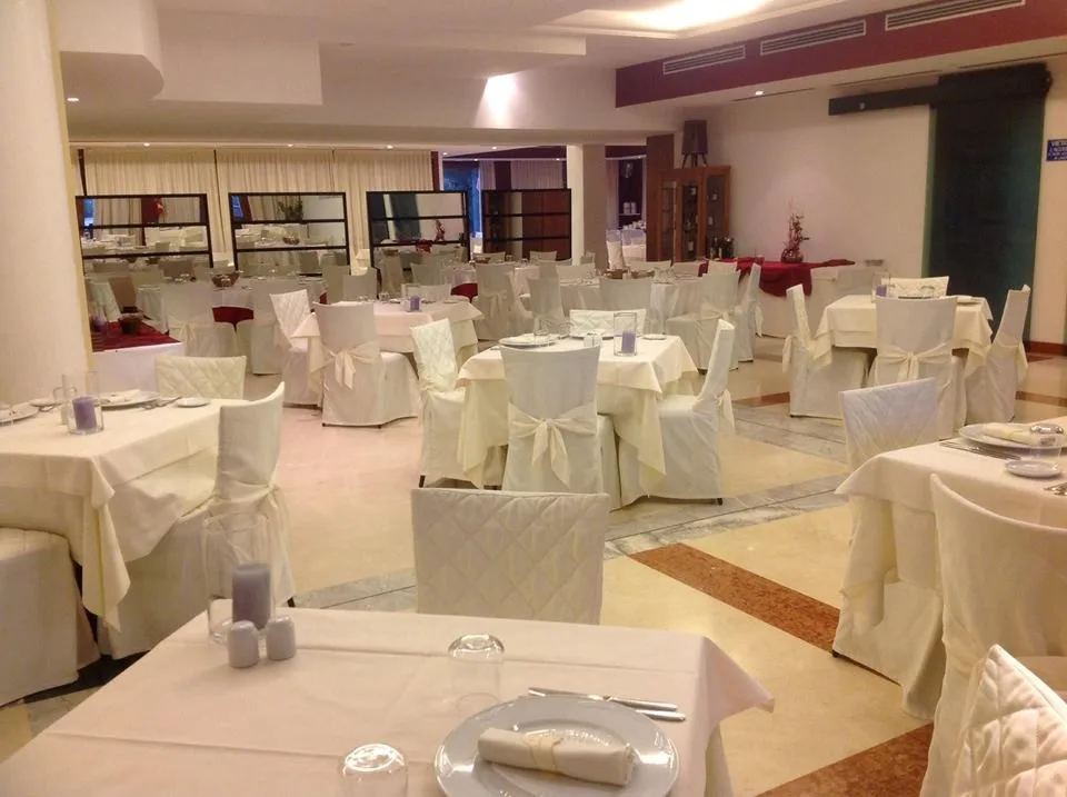 Sala ristorante allestita per banchetti con tavoli e sedie rivestite di bianco