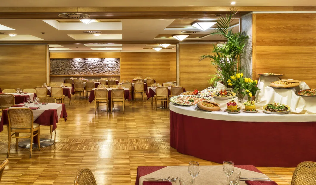 Sala ristorante elegante con ricco buffet di antipasti e tavoli apparecchiati con tovaglie rosse