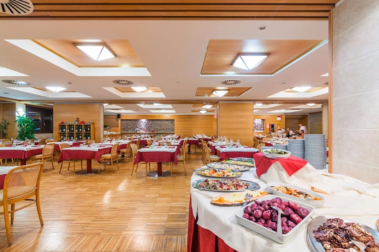 Sala ristorante con buffet di piatti freddi e tavoli apparecchiati con tovaglie rosse