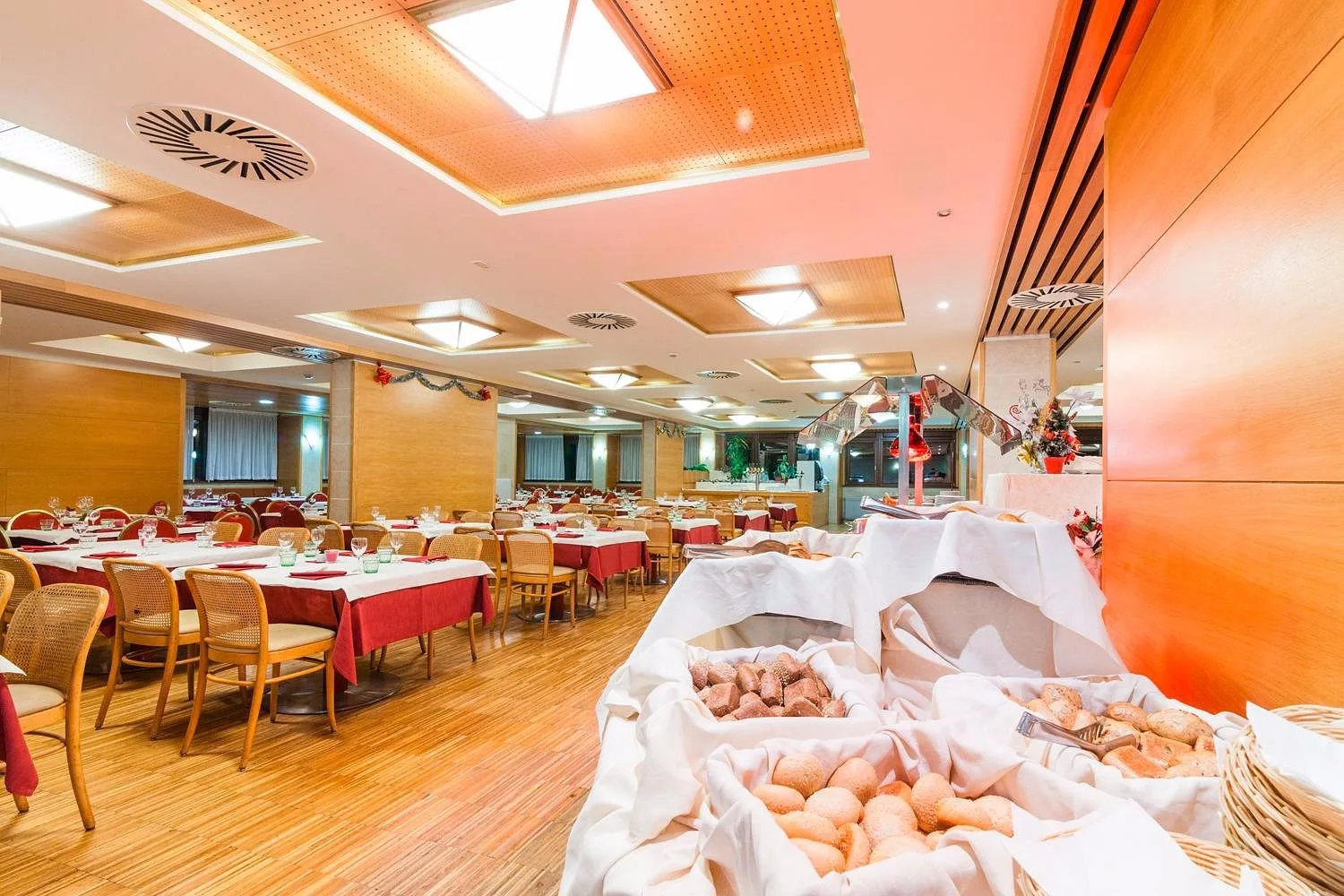 Sala da pranzo dell'hotel con buffet di pane e tavoli apparecchiati con decorazioni natalizie