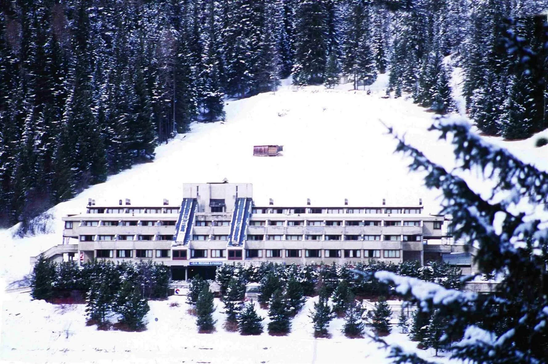 Vista storica dell'hotel immerso nella neve e circondato da boschi di abeti