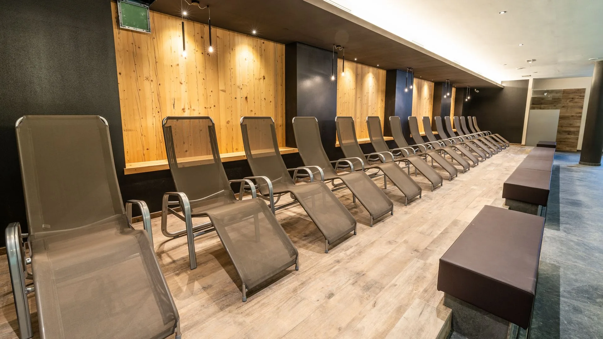 Zona relax della spa con fila di lettini e pareti in legno illuminate