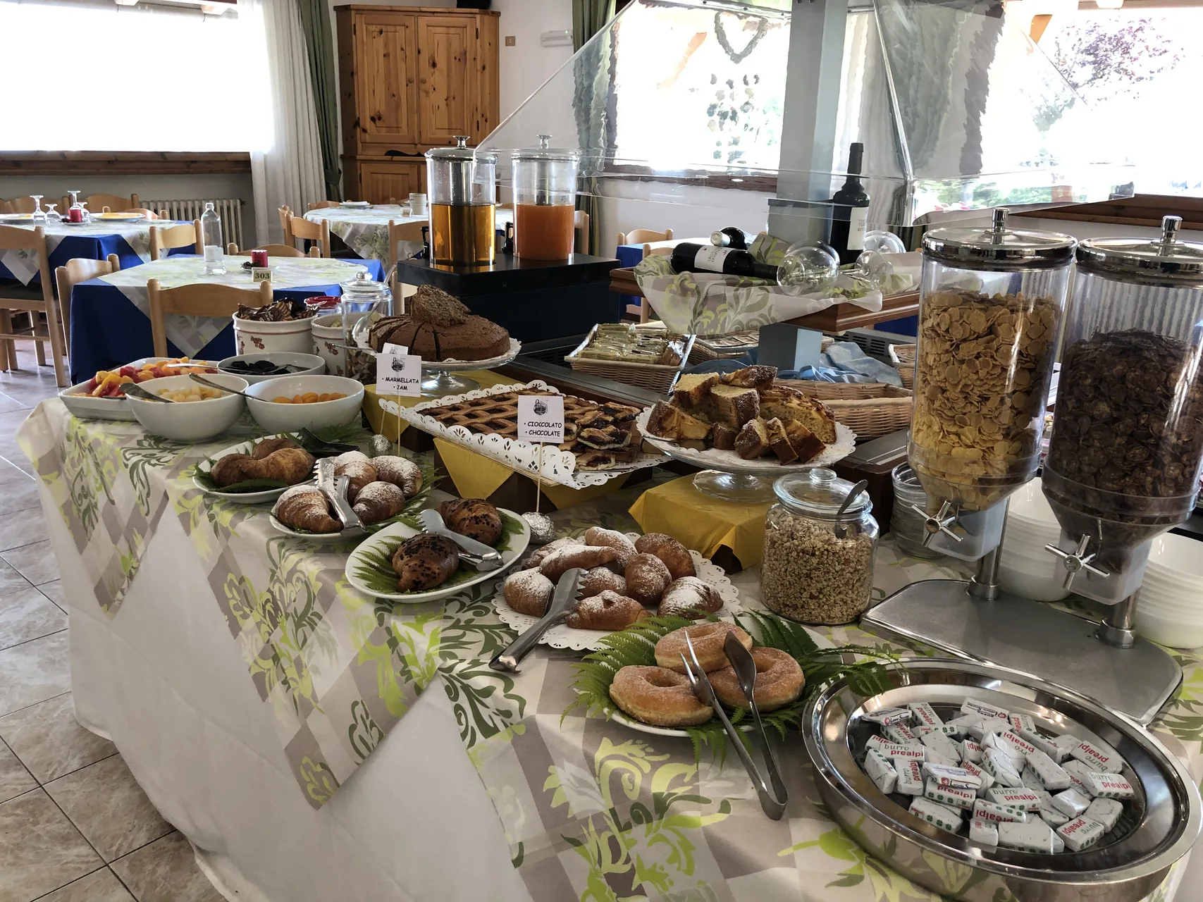 Buffet della prima colazione con dolci, frutta, succhi e distributori di cereali
