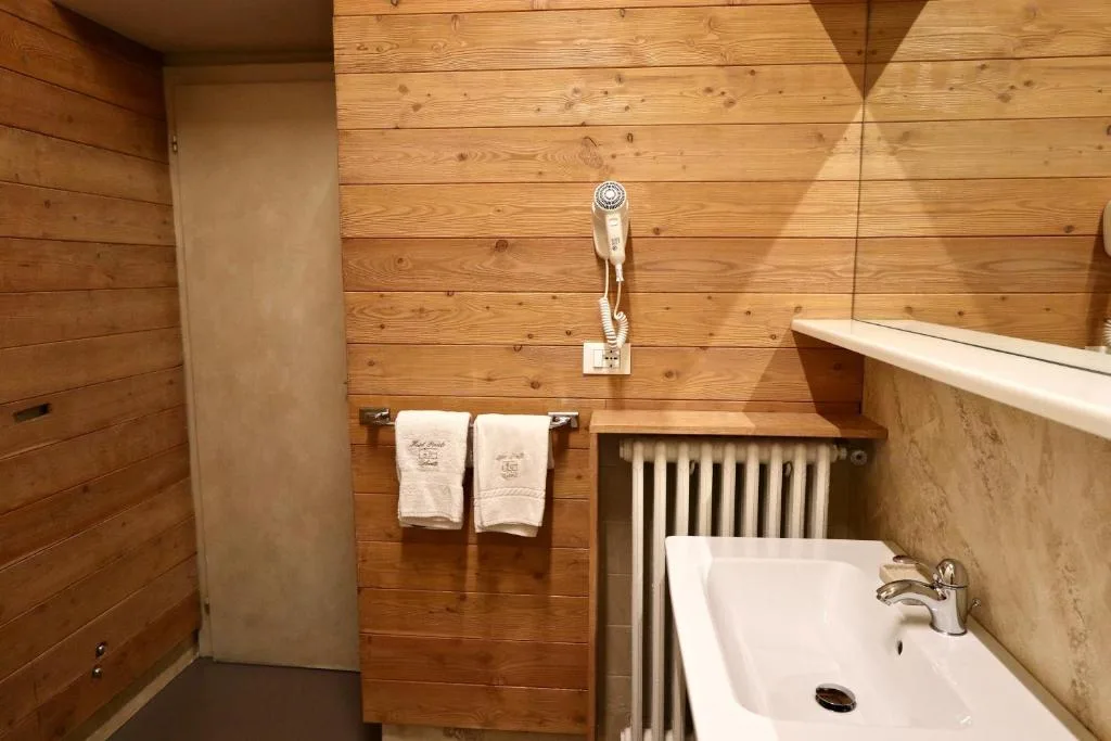 Bagno rivestito in legno con lavabo, specchio, asciugacapelli e asciugamani