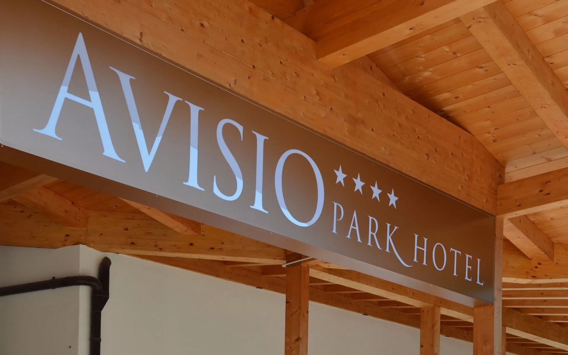 Insegna Avisio Park Hotel sotto la struttura in legno all'ingresso