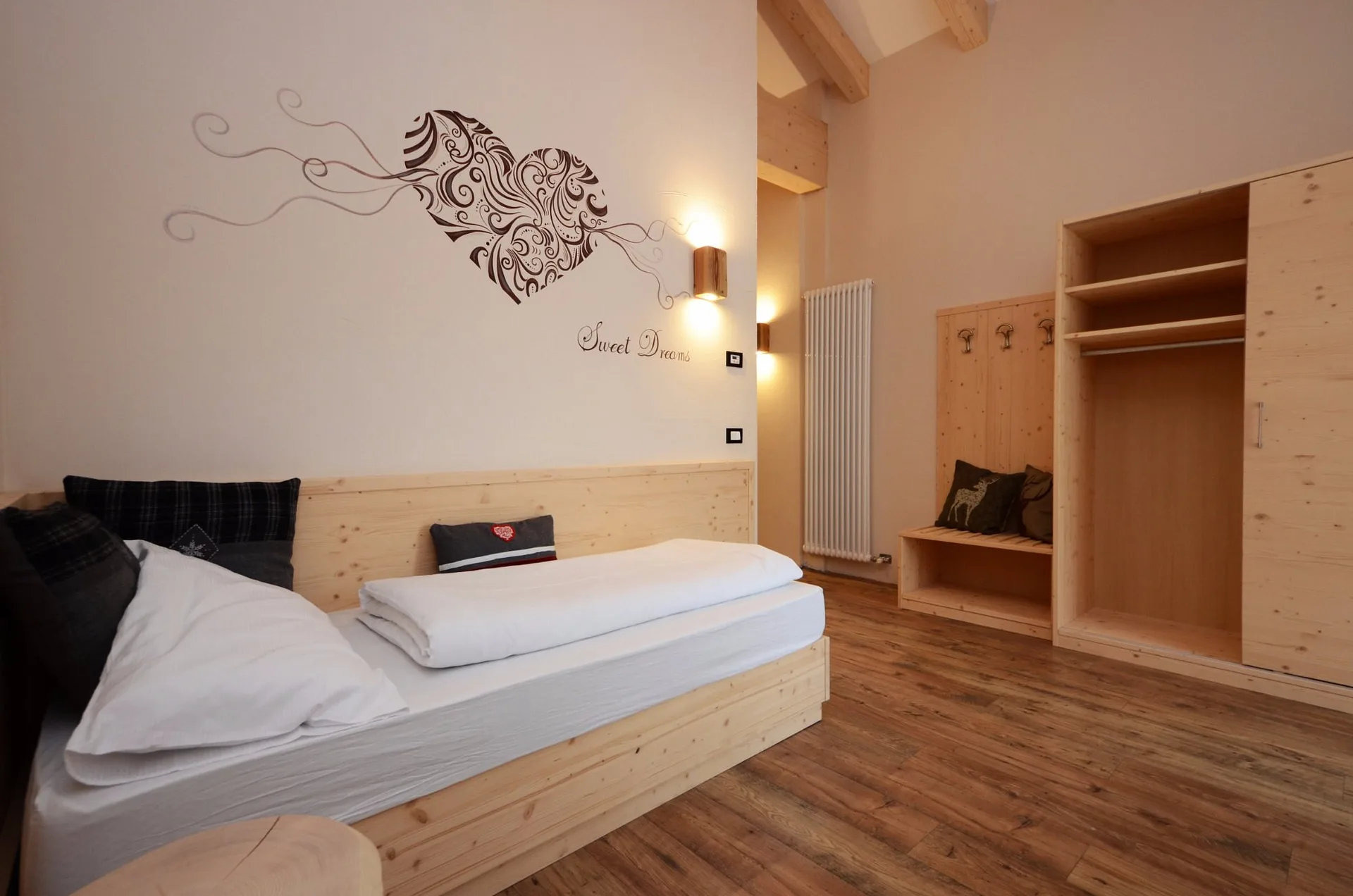 Camera con decorazione a cuore sulla parete, armadio e arredo in legno chiaro