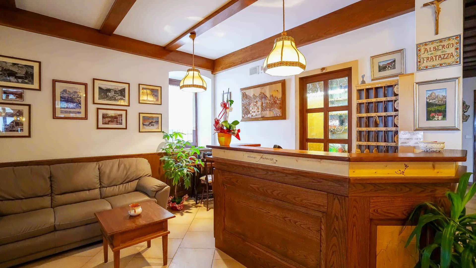 Reception dell'albergo con banco in legno e divano nella hall accogliente