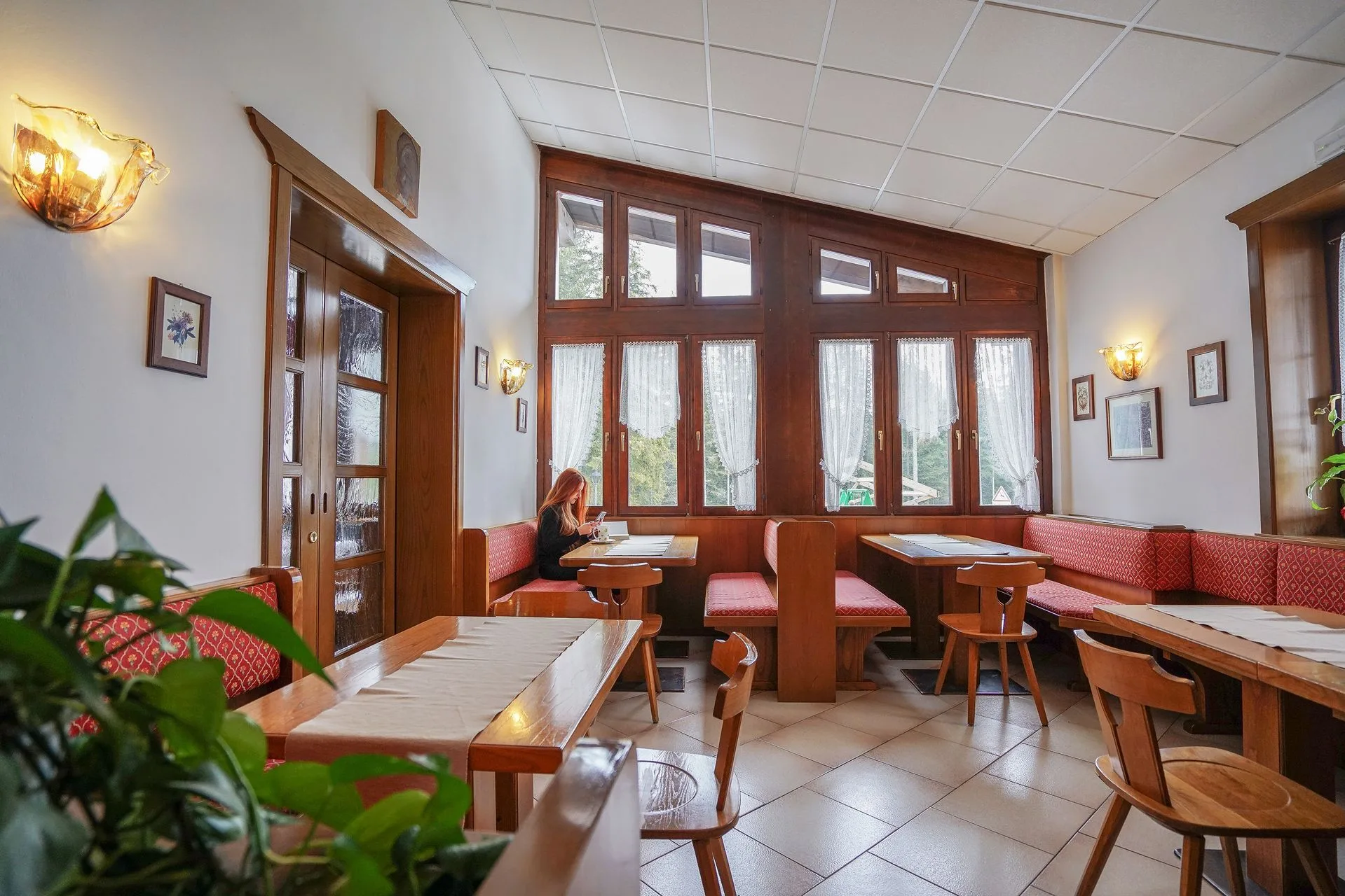 Sala interna con tavoli in legno, panche rosse e ampie finestre