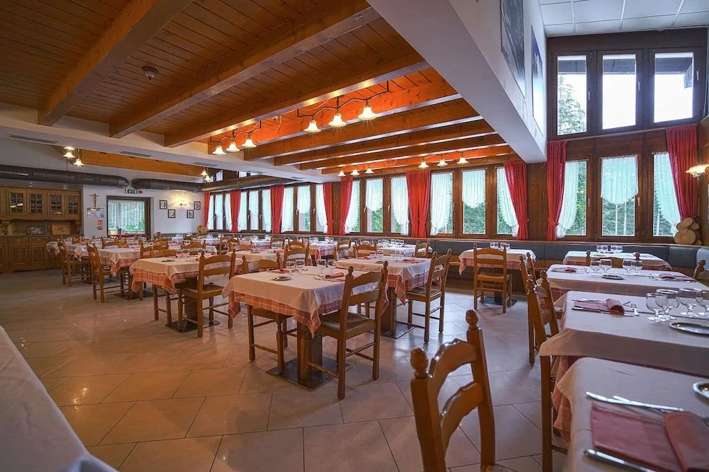 Sala ristorante con tavoli apparecchiati e tende rosse
