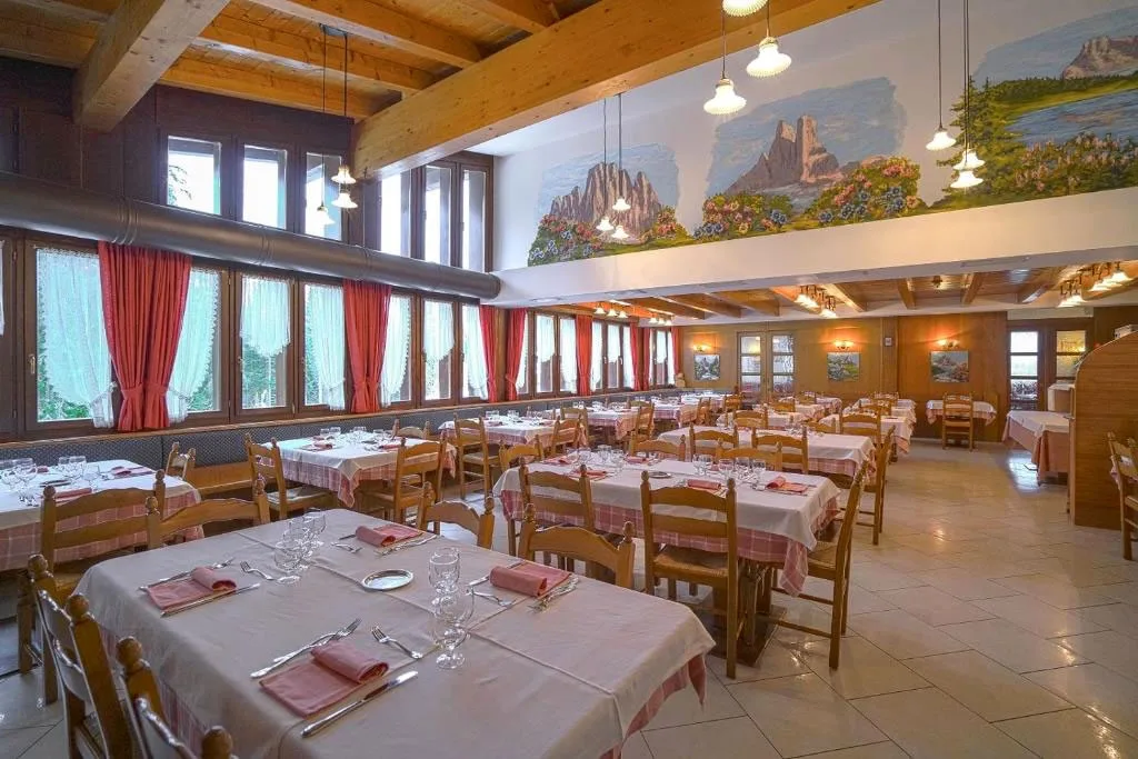 Sala da pranzo con affreschi di montagna e tavoli imbanditi