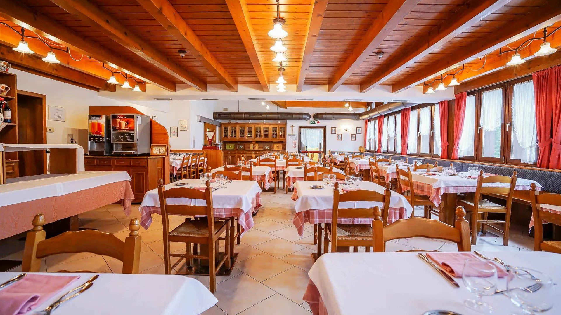 Ampia sala ristorante con soffitto in legno e tovaglie a quadretti