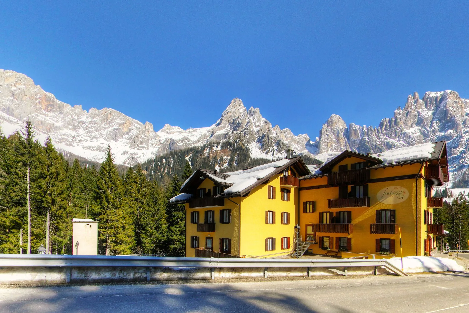 L'hotel giallo con le Pale di San Martino innevate e cielo azzurro