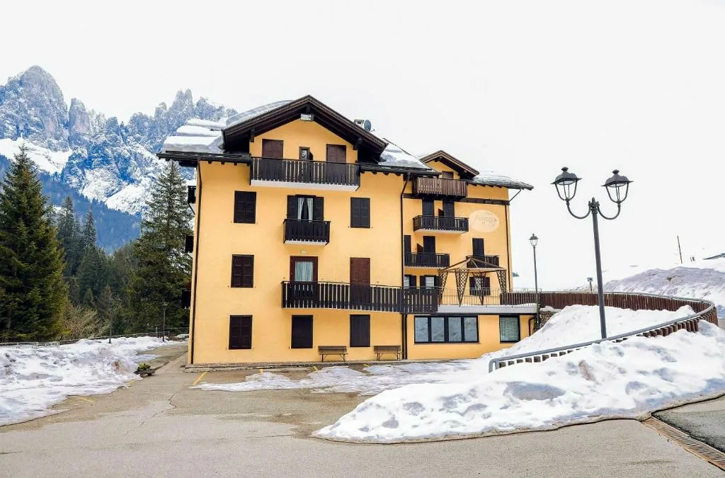 Facciata dell'albergo con cime dolomitiche innevate sullo sfondo