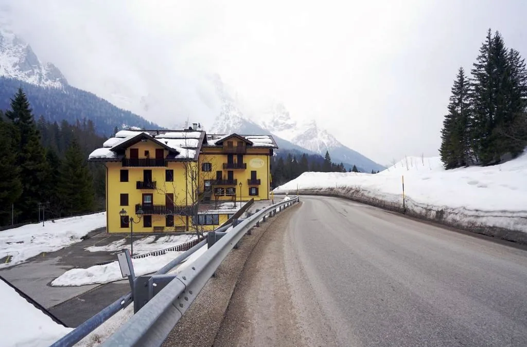 L'albergo giallo lungo la strada innevata con montagne nella nebbia