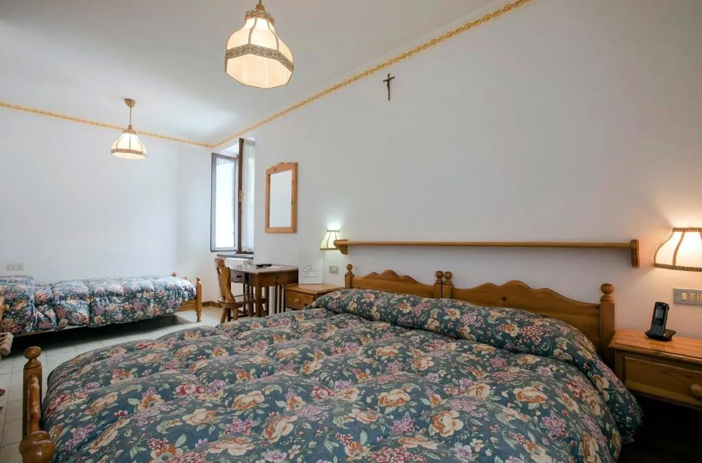 Camera tripla con arredi in legno e biancheria a fiori