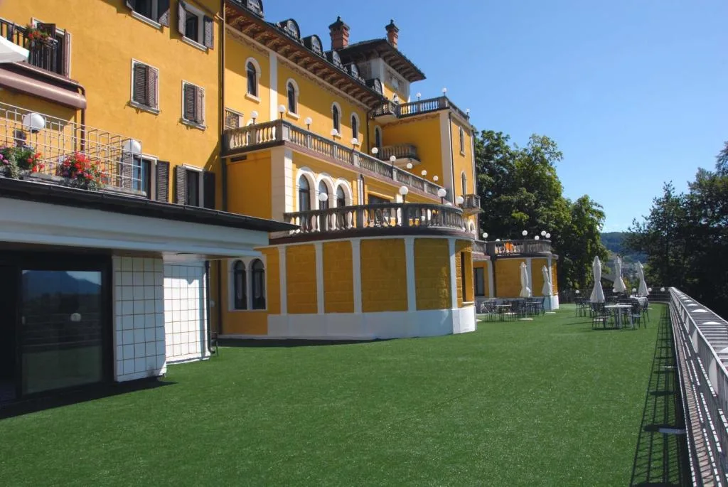 Ampia terrazza in erba sintetica accanto alla facciata gialla dell'hotel
