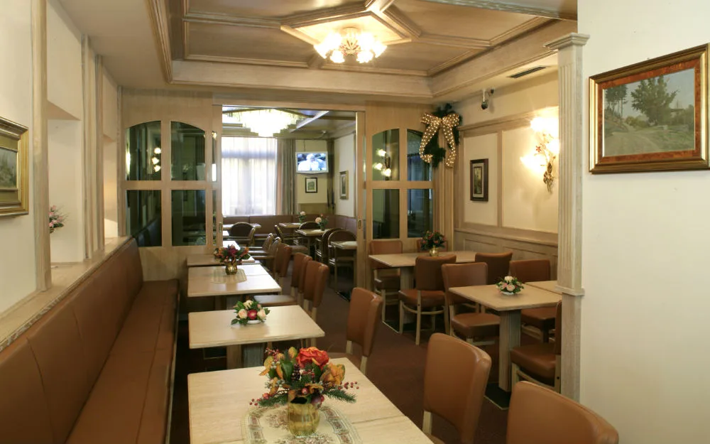 Sala colazione elegante con tavoli, sedute in pelle marrone e decorazioni natalizie