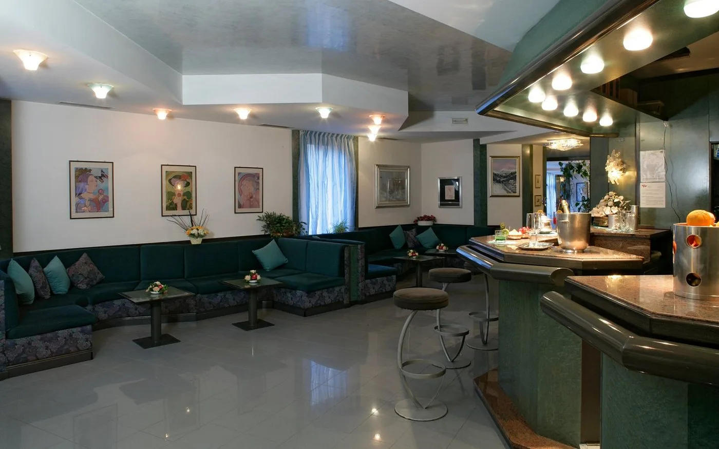 Area lounge bar con divani verdi, sgabelli e bancone in stile classico