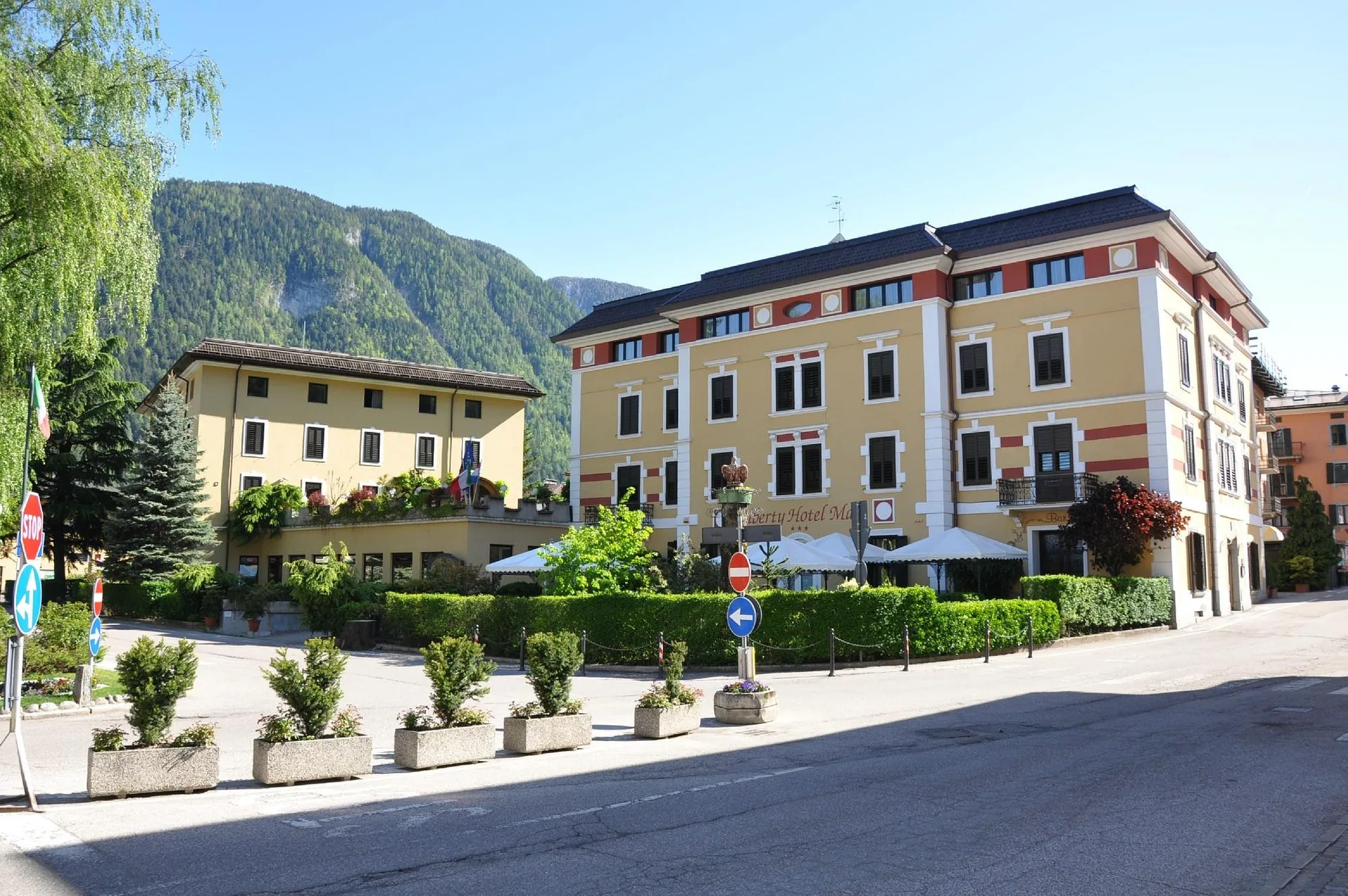 Vista estiva del Liberty Hotel Malè con montagne verdi e cielo azzurro