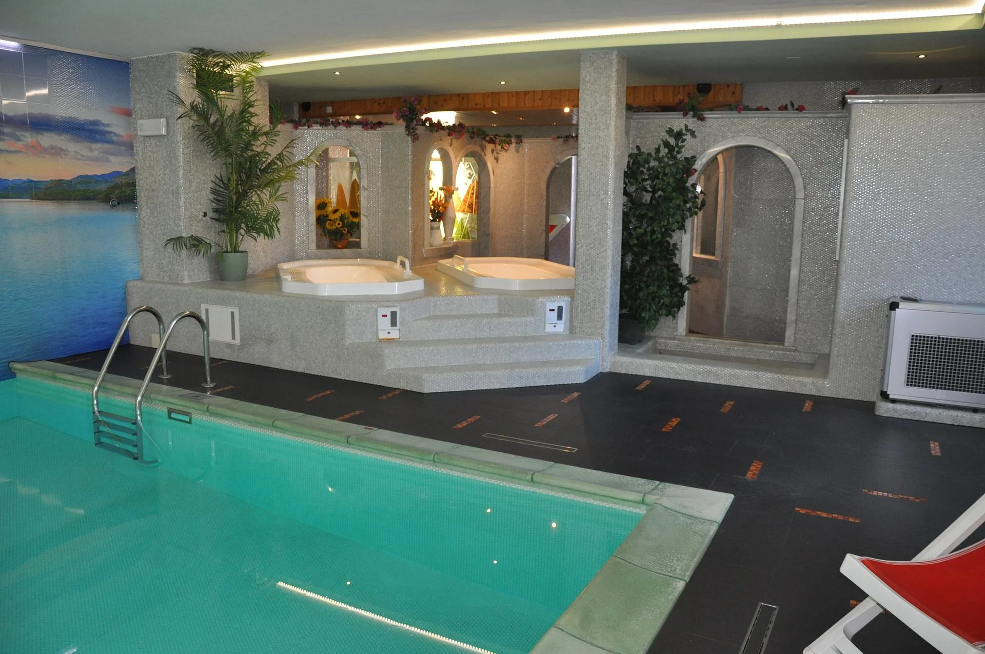 Piscina interna con vasche idromassaggio e murale panoramico di lago