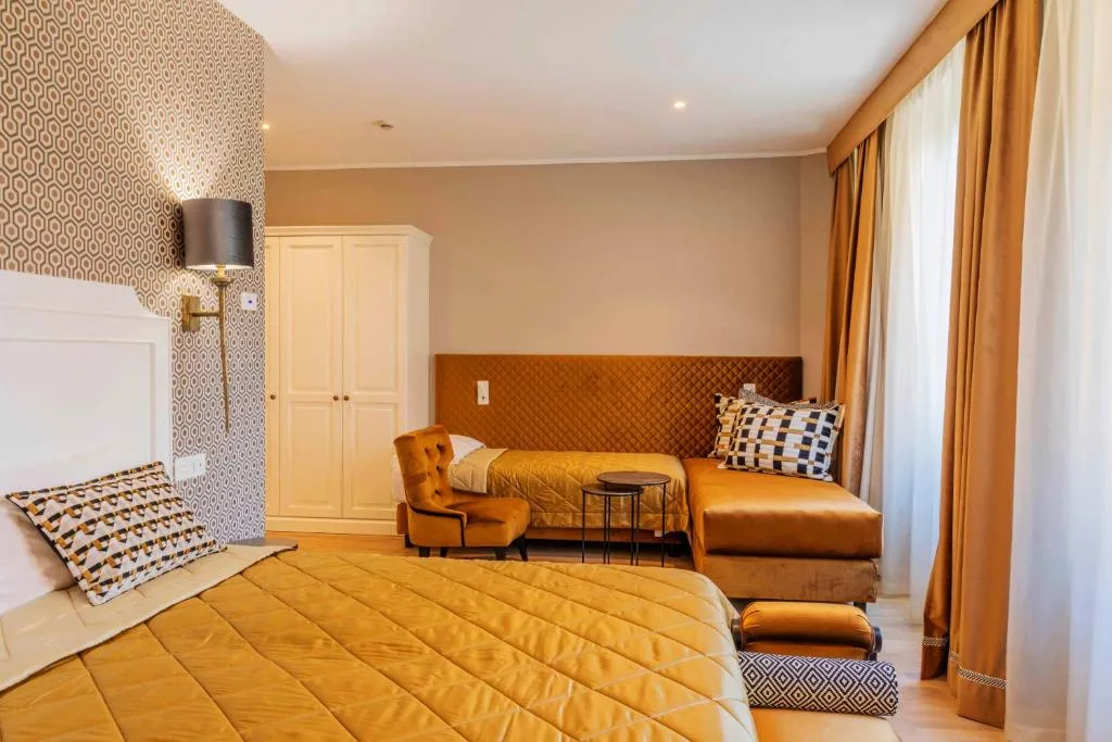 Camera elegante con letto matrimoniale, divano e parete decorata a motivi geometrici