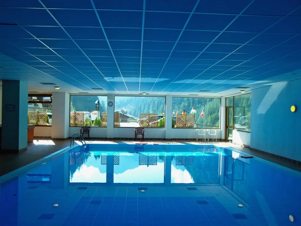 Piscina interna con vetrate panoramiche sui boschi di montagna