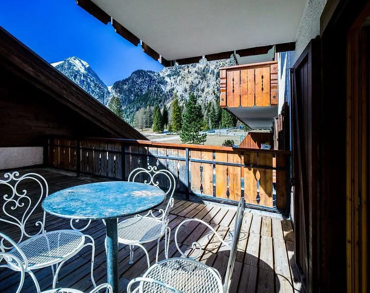 Balcone in legno con tavolino e sedie affacciato sulle montagne innevate