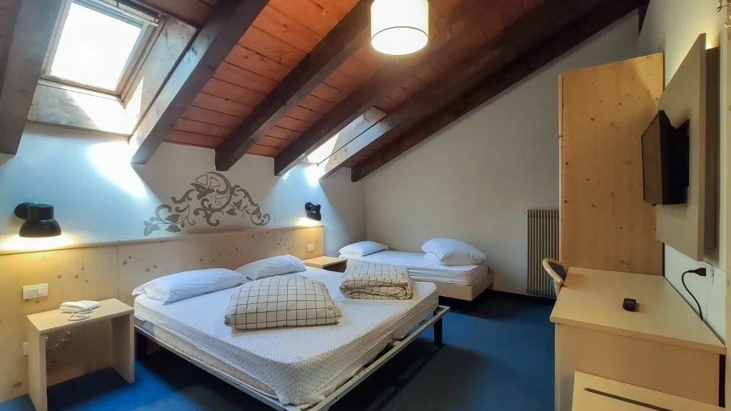 Camera mansardata con travi in legno, letti e lucernari