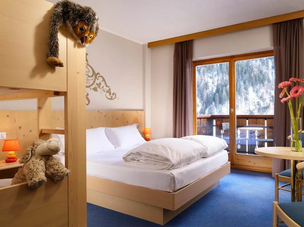 Camera familiare con letto matrimoniale, letto a castello e balcone sul bosco