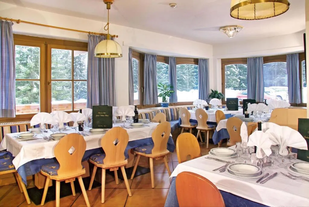 Sala ristorante con tavoli apparecchiati, sedie in legno e ampie finestre con vista sulla neve