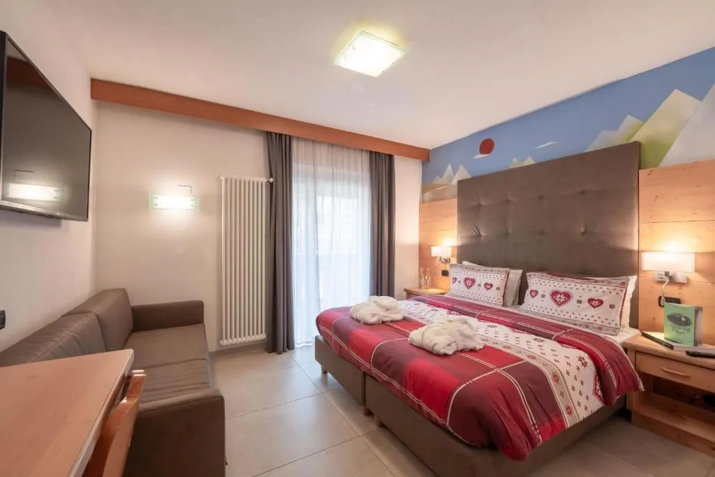 Camera moderna con letto matrimoniale, divano, TV a parete e decoro montano azzurro