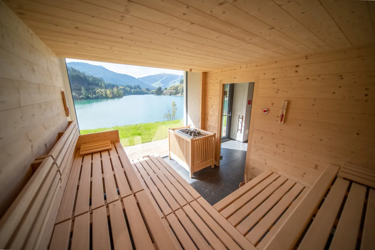 Sauna finlandese in legno con grande finestra panoramica sul lago