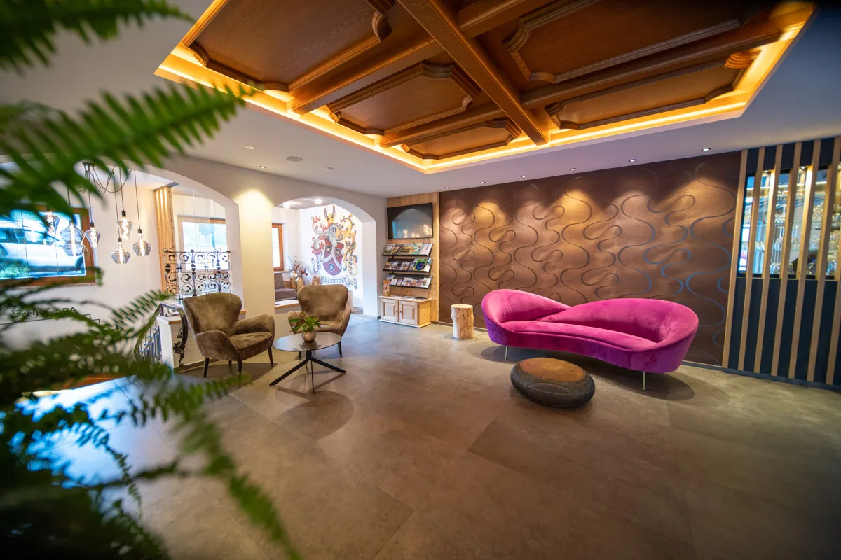 Zona lounge della hall con divano rosa e poltrone in velluto