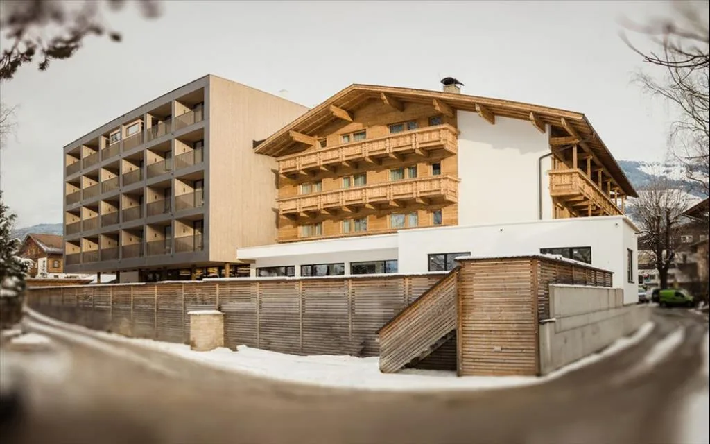 Facciata dell'hotel con struttura moderna e chalet tradizionale in legno