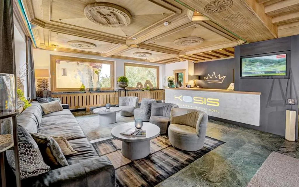 Lounge e reception dell'hotel Kosis con divani, soffitto in legno intagliato e arredi eleganti