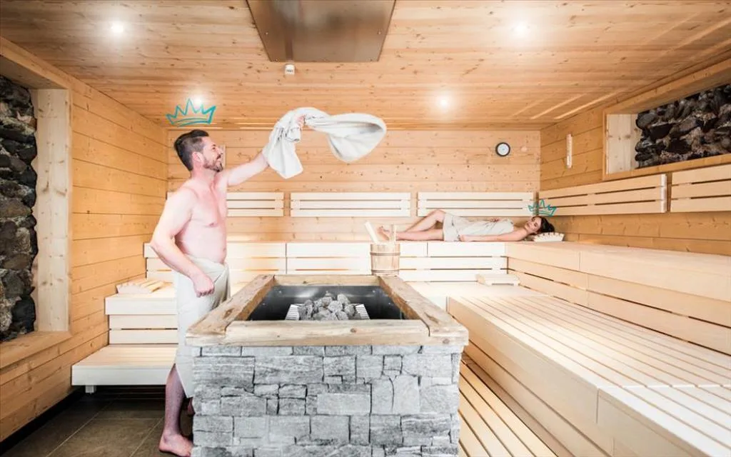 Sauna finlandese in legno con ospiti durante il rituale del gettito di vapore