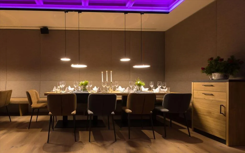 Sala ristorante privata con tavolo lungo apparecchiato e luci a sospensione