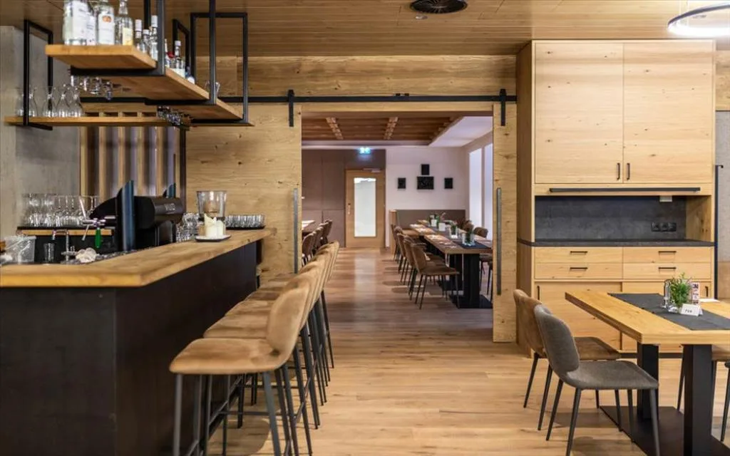 Bar interno con bancone in legno, sgabelli e area ristorante