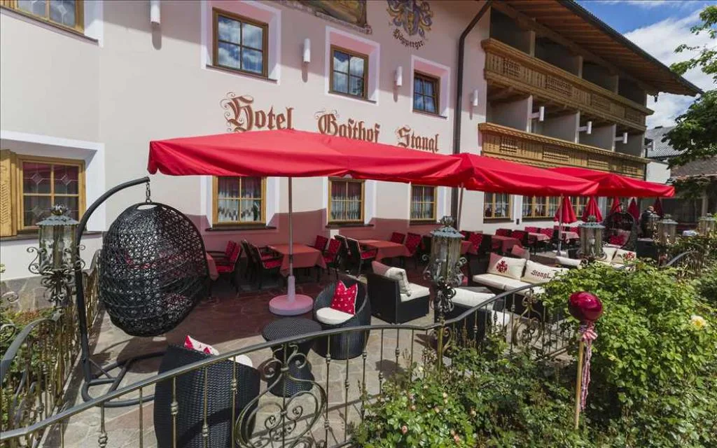 Terrazza esterna dell'hotel con divani in rattan, cuscini rossi e ombrelloni rossi