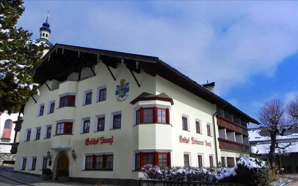 Facciata dell'hotel innevata con stemma decorativo e finestre con persiane rosse