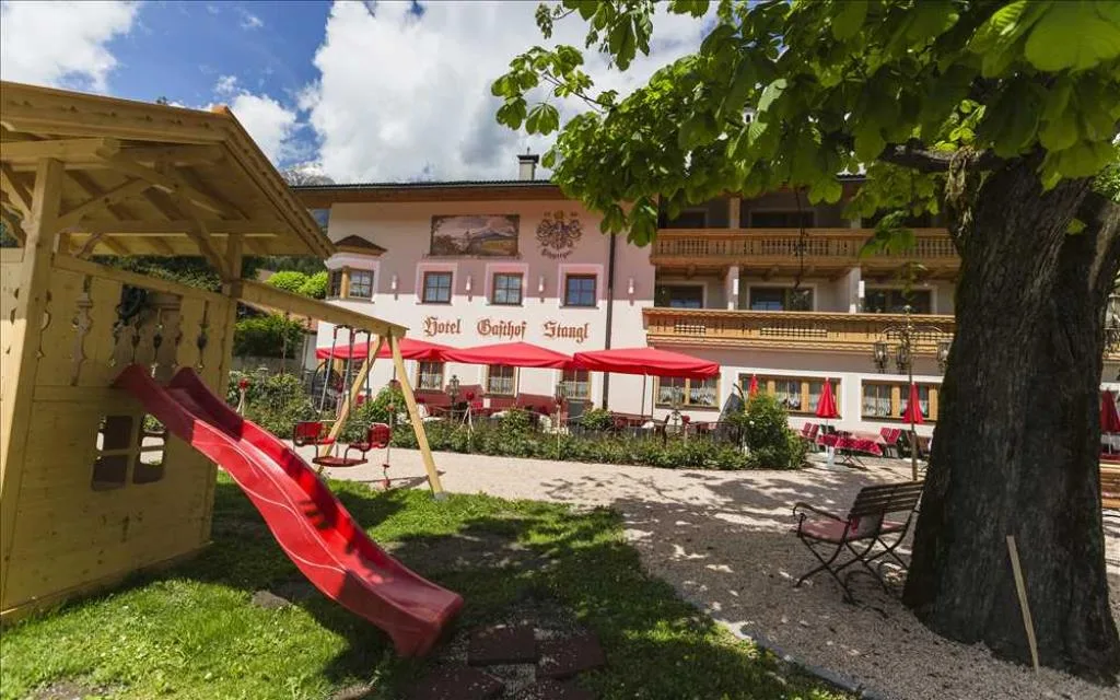 Giardino dell'hotel con area giochi per bambini, scivolo rosso e terrazza sullo sfondo