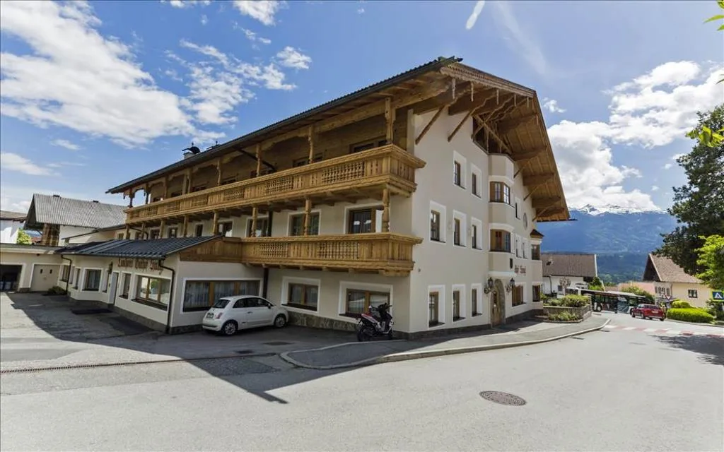 Esterno dell'hotel con balconi in legno, vista sulla strada e montagne sullo sfondo